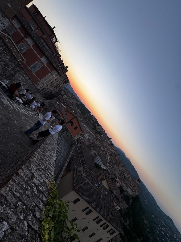 Perugia bei Sonnenuntergang, gesehen von einer hoch gelegenen Steinterrasse.