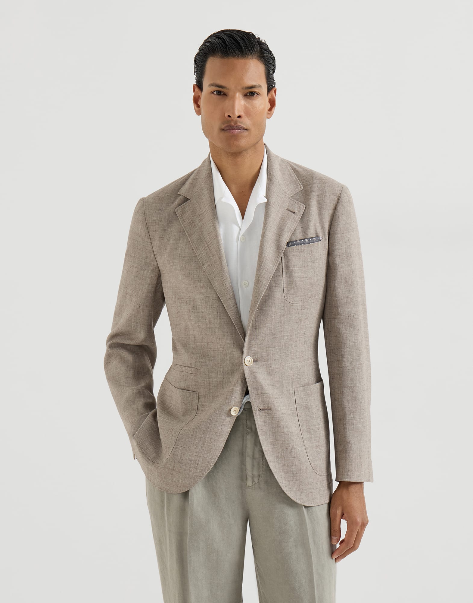 A model wearing a light taupe Brunello Cucinelli deconstructed blazer.