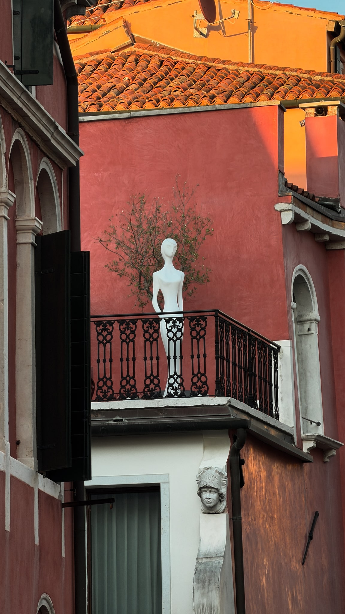 Una figura en un balcón, entre paredes de terracota.