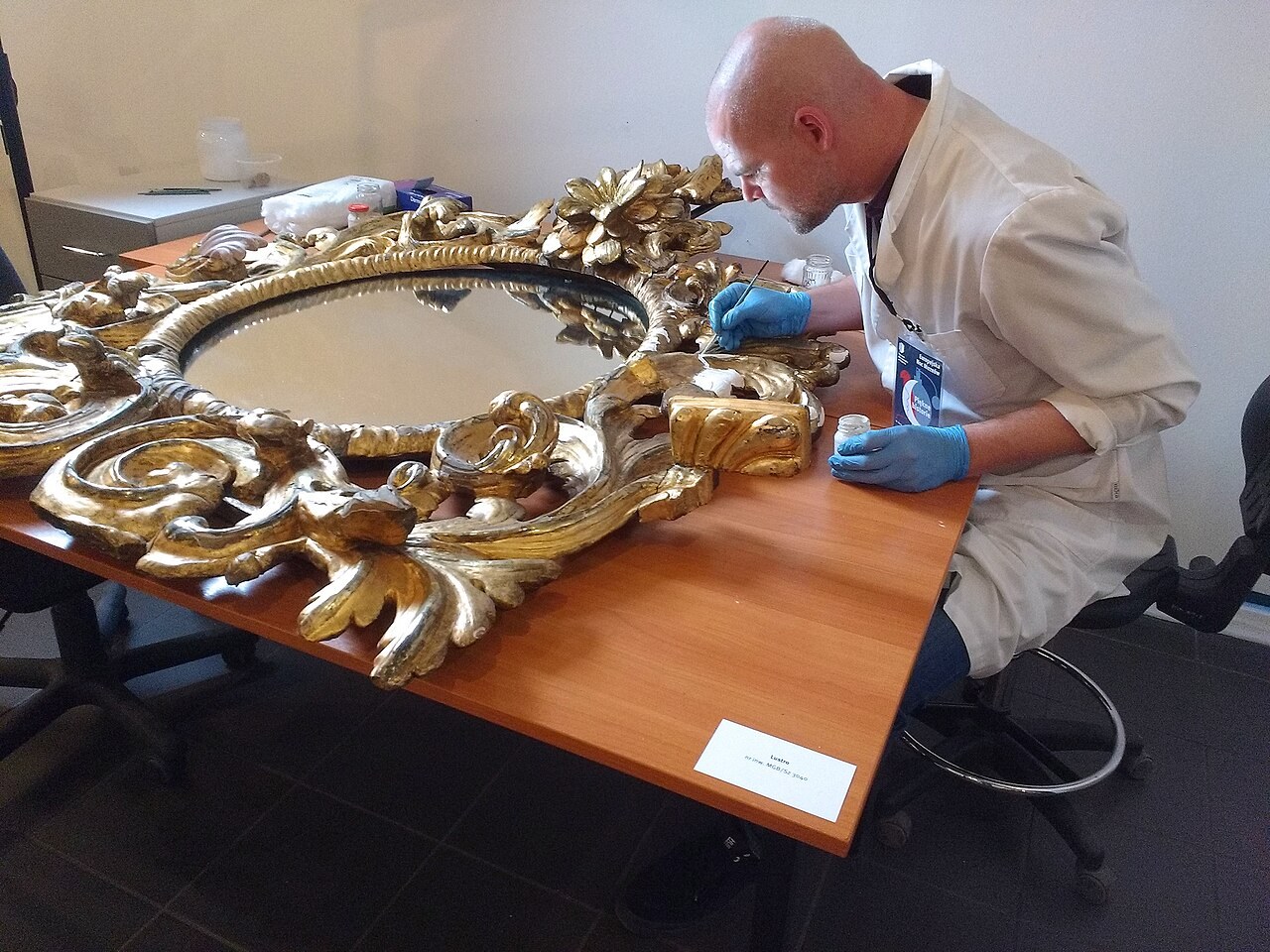 A restorer working on a gilded mirror in a museum