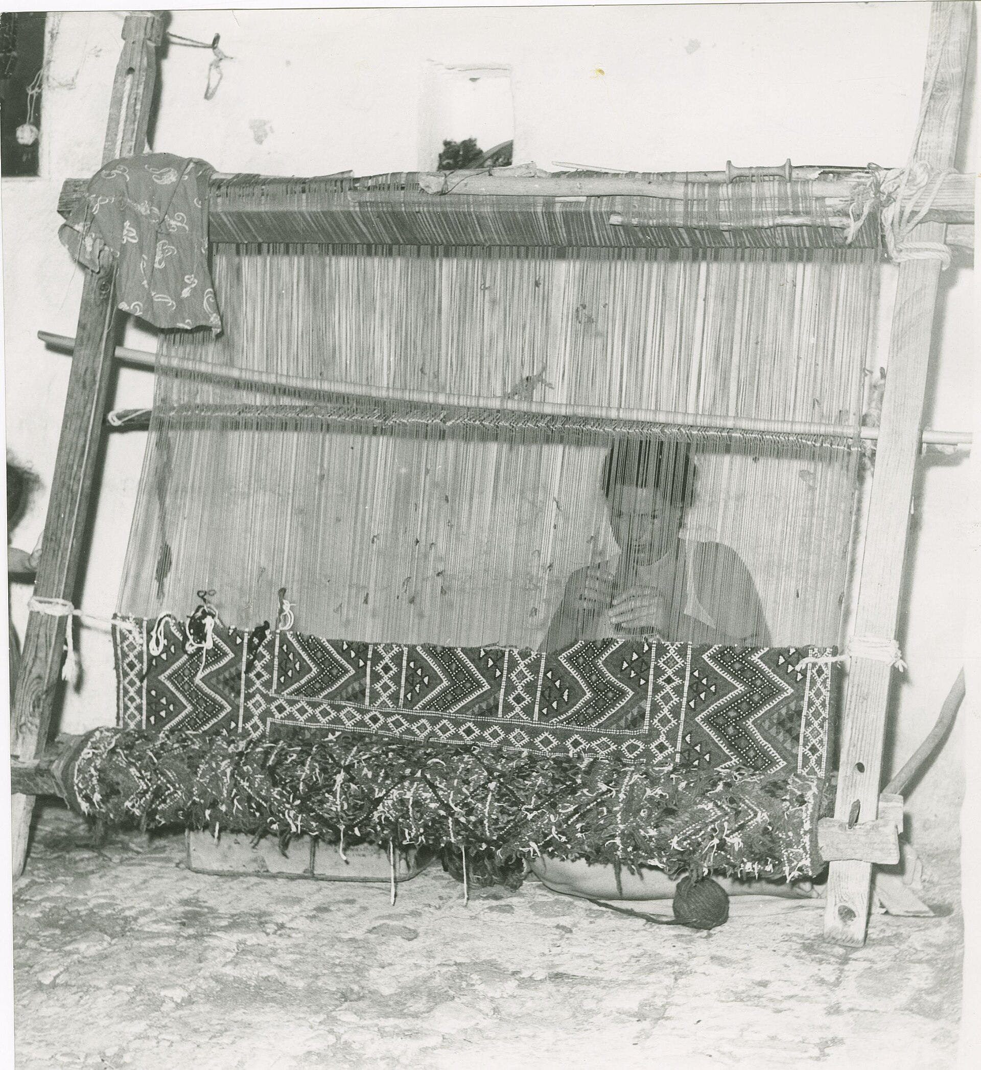 A woman weaving a carpet by hand in a 1961 archival photograph