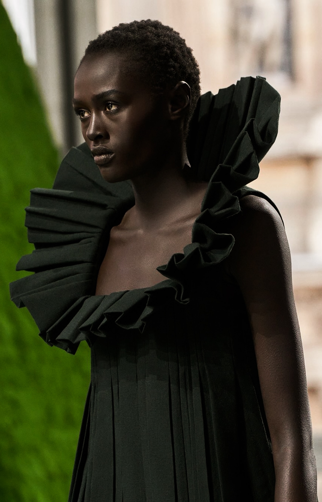 Black pleated dress with a sculptural ruffled neckline.