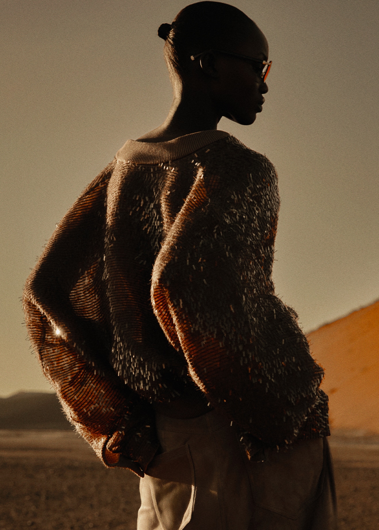 Textured bronze knitwear and glasses in warm side light.