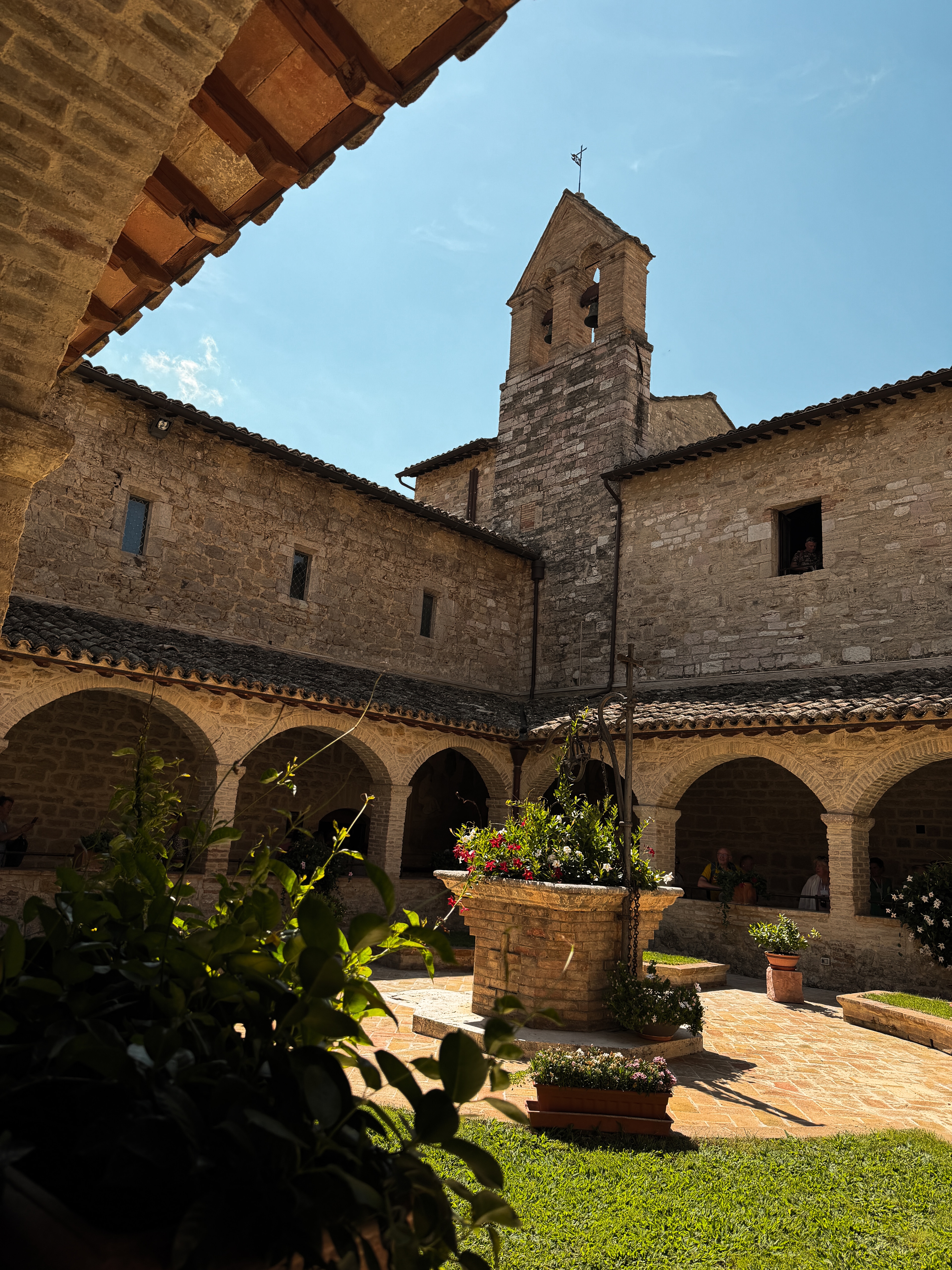 Um pátio de pedra e o campanário de San Damiano, em Assis.