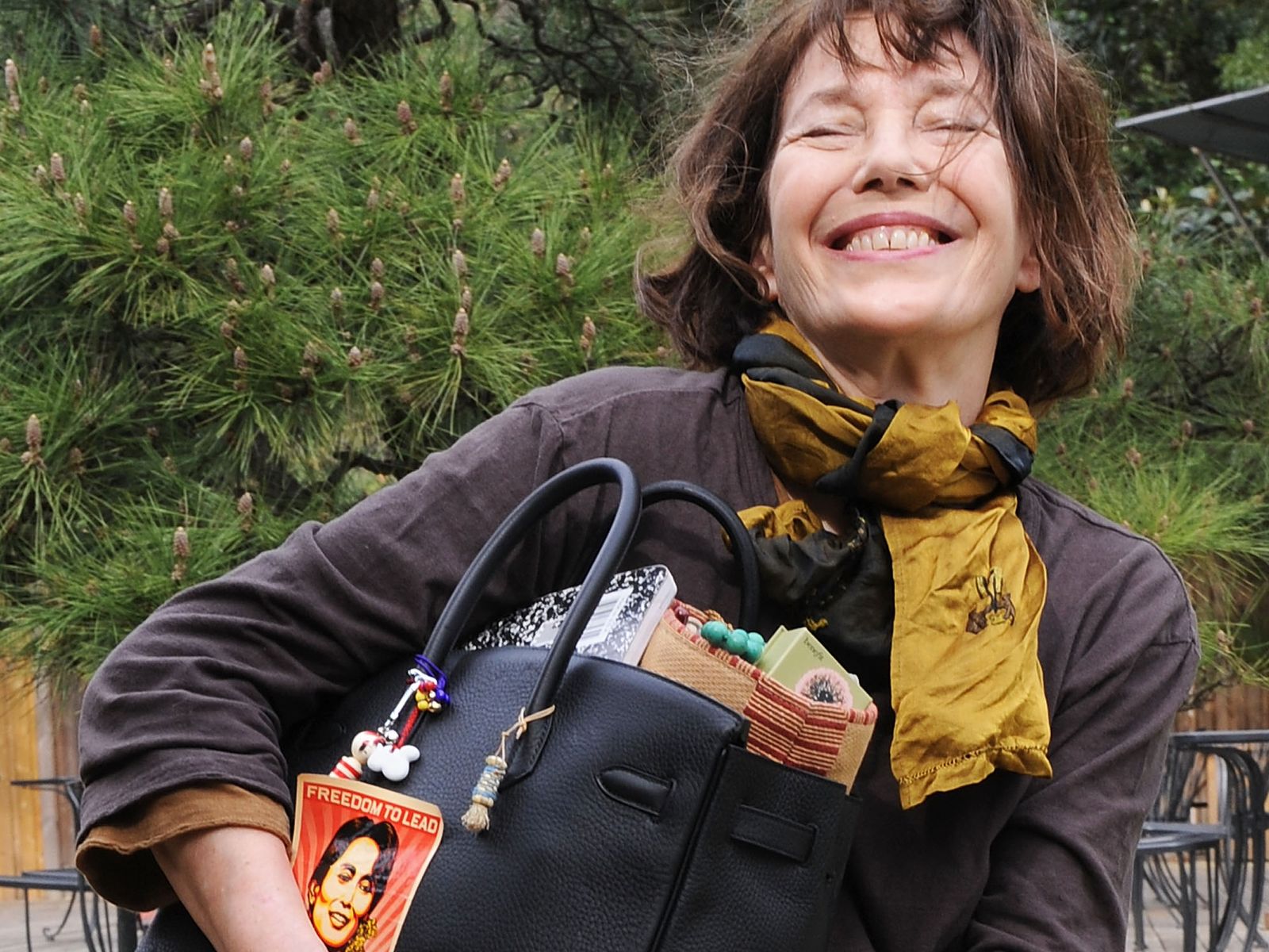 Jane Birkin sonríe mientras sostiene su Birkin personalizado.